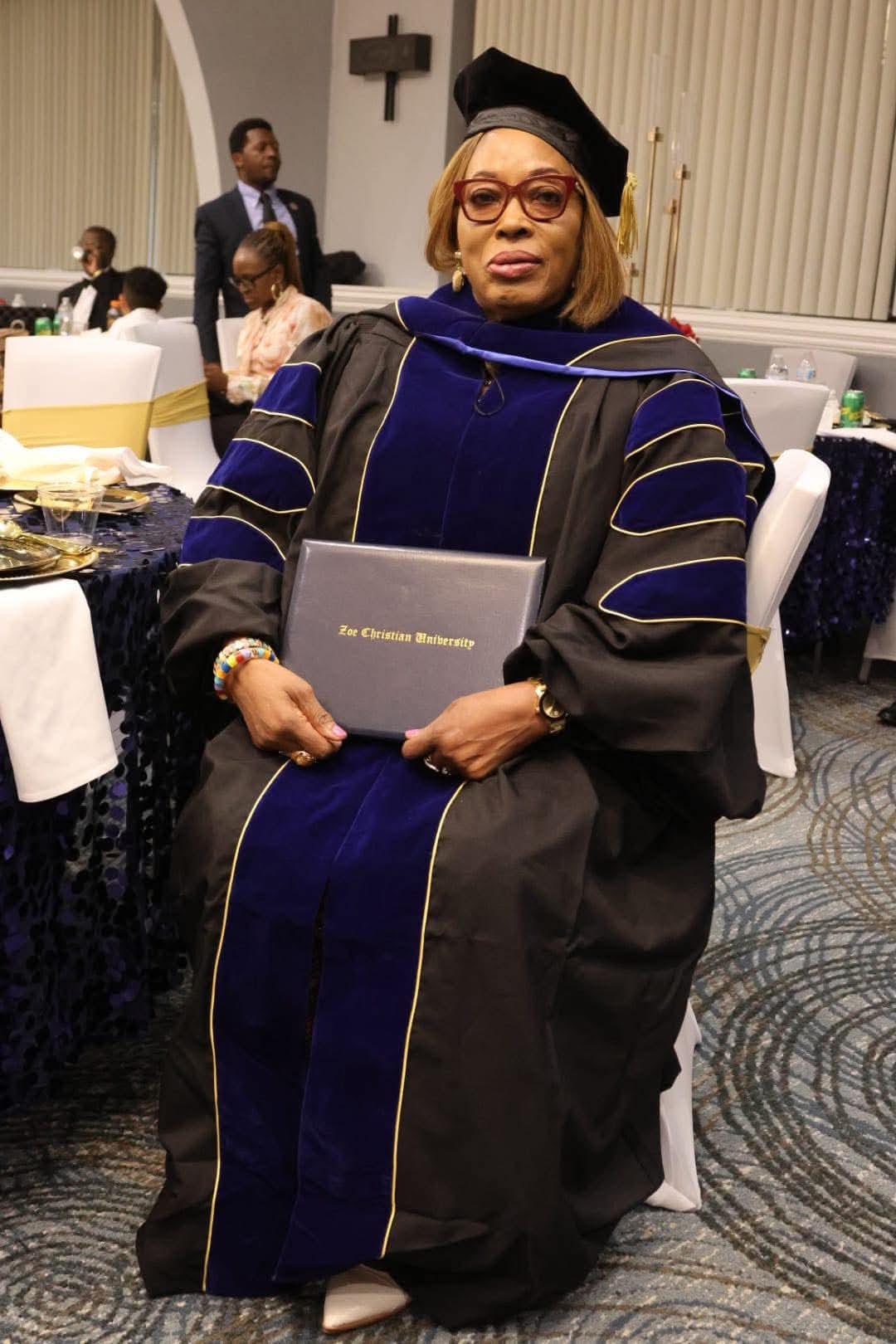 Doctoral graduate seated with her Zoe Christian University diploma