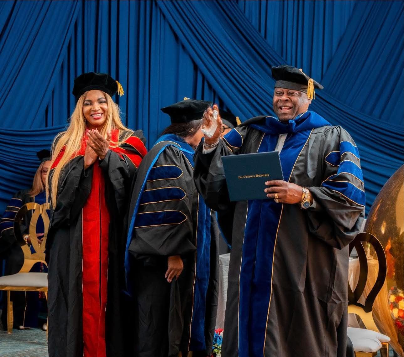 Applause as a graduate receives his Zoe Christian University diploma