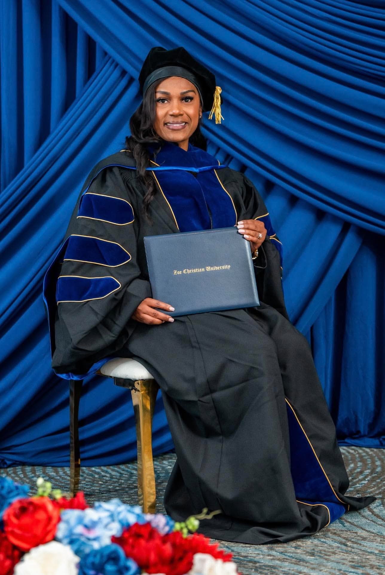 Doctoral graduate seated with her Zoe Christian University diploma folder