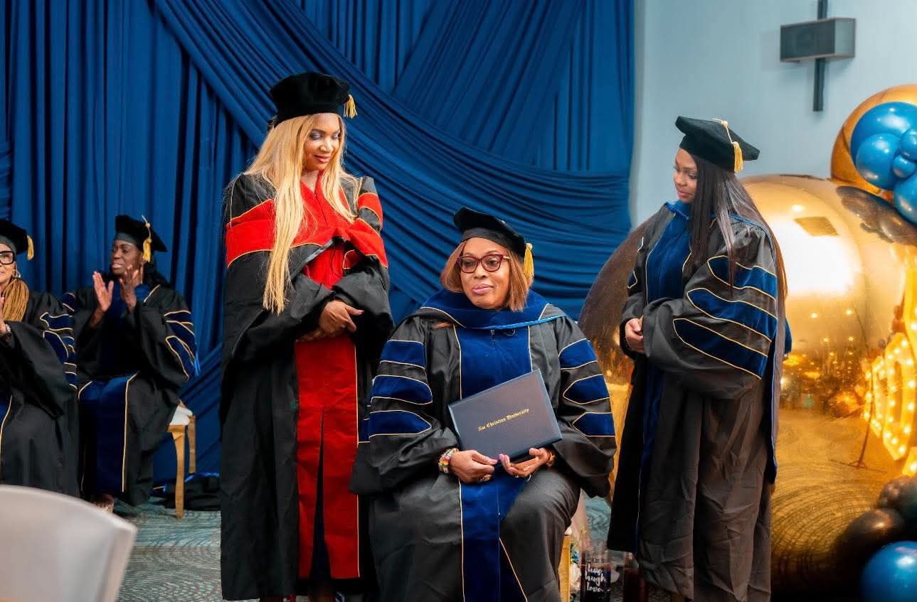 Faculty applauding a Zoe Christian University graduate