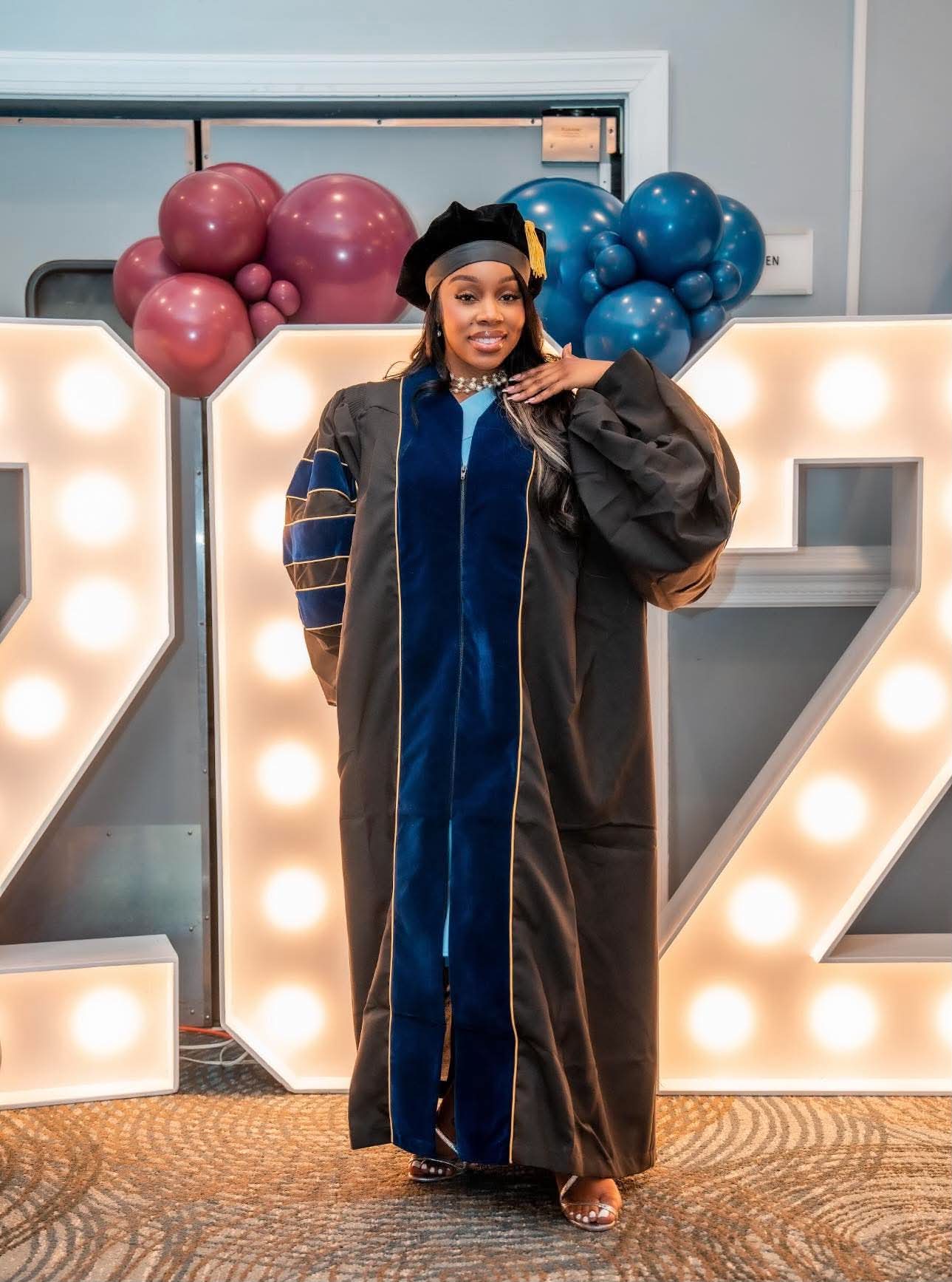 Graduate posing in front of the illuminated ZCU marquee letters