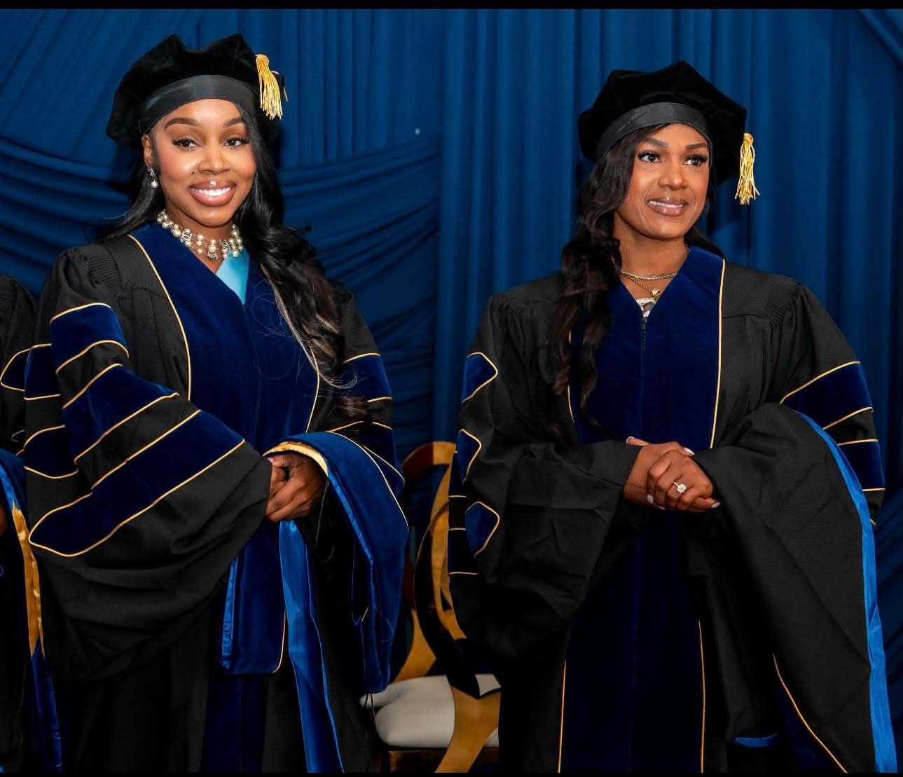 Two doctoral graduates in navy and gold regalia
